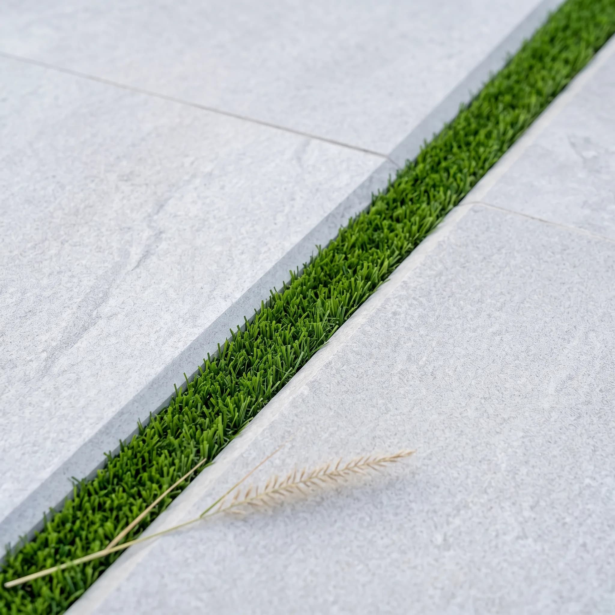 Extreme close-up of the porcelain-tile-to-artificial-grass joint, the signature material detail of the desert-modern style